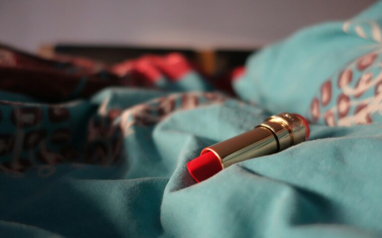 a red lipstick resting on a blue blanket