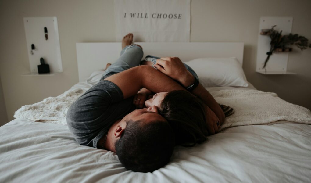 A man and woman cuddling together in bed.