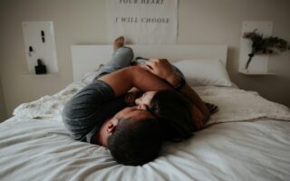 A man and woman cuddling together in bed.