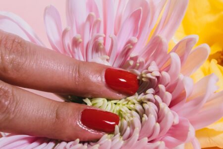 person pressing a chrysanthemum flower on pink surface